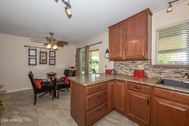 kitchen with backsplash, kitchen peninsula, sink, rail lighting, and ceiling fan