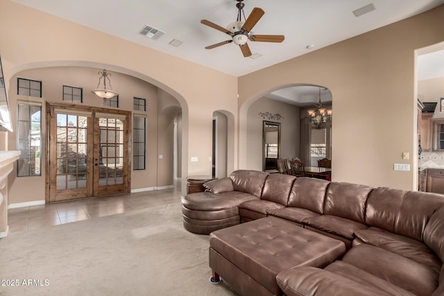 carpeted living area with tile patterned flooring, visible vents, baseboards, and ceiling fan with notable chandelier