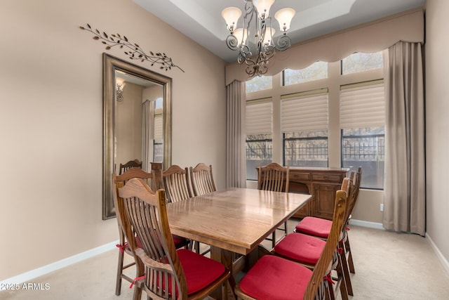 dining room featuring baseboards, a raised ceiling, light colored carpet, and an inviting chandelier