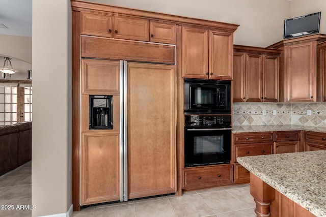 kitchen featuring decorative backsplash, brown cabinetry, black appliances, and light stone countertops