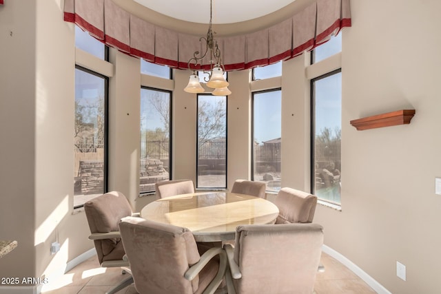 dining room featuring light tile patterned floors, a towering ceiling, and baseboards