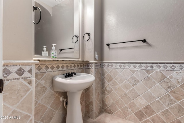 bathroom with wainscoting and tile walls