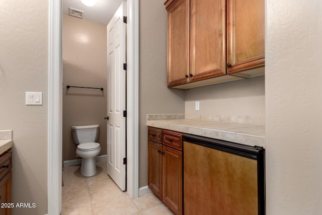 bathroom featuring visible vents, toilet, vanity, tile patterned flooring, and baseboards