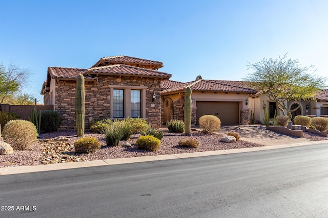 view of front of house with an attached garage, a tile roof, stone siding, driveway, and stucco siding