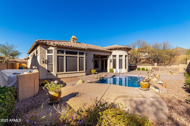 back of property with a fenced in pool, a chimney, stucco siding, a patio area, and a tiled roof