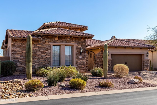 mediterranean / spanish-style home featuring stucco siding, a garage, stone siding, driveway, and a tiled roof