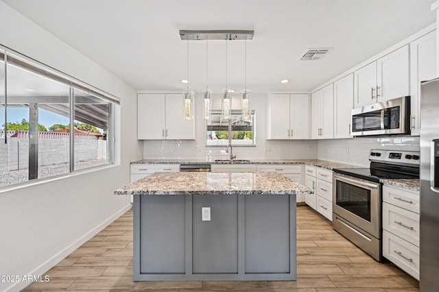 1017 S Allen, Mesa, AZ 85204 - kitchen with stainless steel appliances, backsplash, a center island, white cabinets, and light wood-style flooring