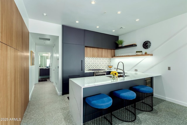 kitchen with a kitchen bar, high end stainless steel range, sink, a center island, and backsplash