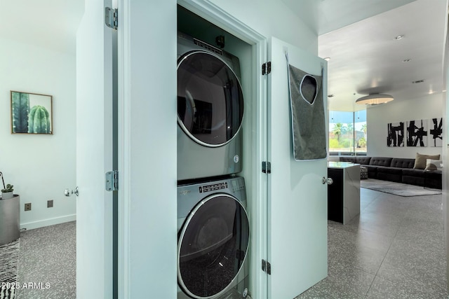 clothes washing area with stacked washing maching and dryer