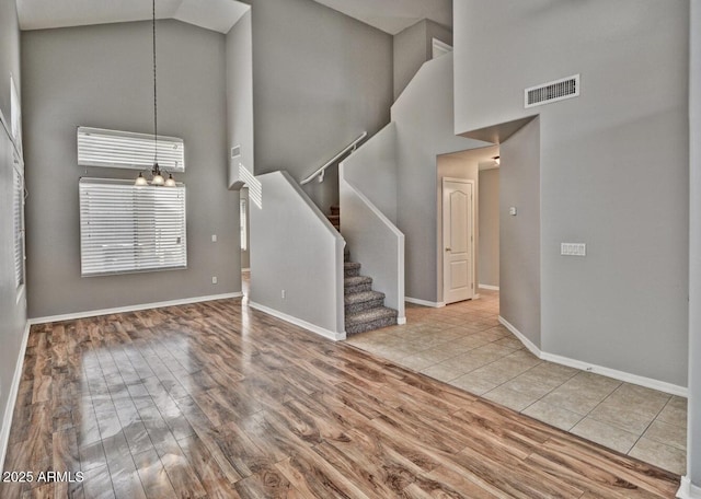 interior space with a notable chandelier, high vaulted ceiling, and light hardwood / wood-style flooring