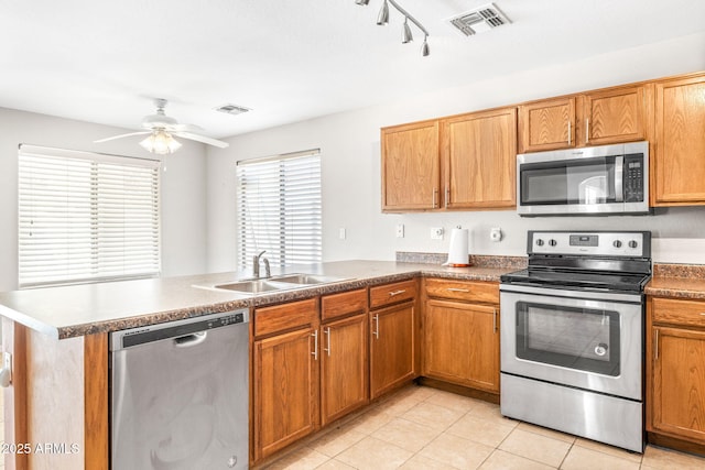 kitchen featuring sink, light tile patterned floors, ceiling fan, stainless steel appliances, and kitchen peninsula