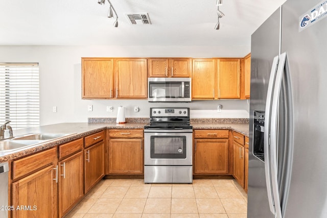 kitchen featuring appliances with stainless steel finishes, sink, light tile patterned floors, kitchen peninsula, and track lighting