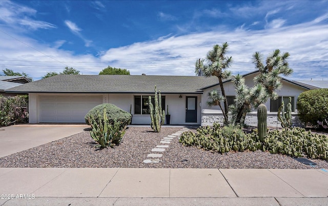 ranch-style home with concrete driveway, a shingled roof, and an attached garage