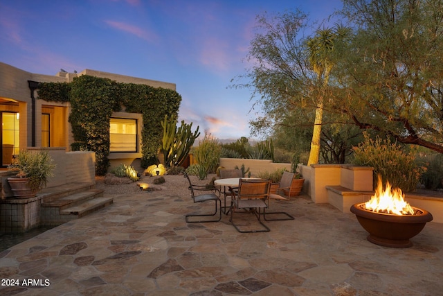 patio terrace at dusk featuring a fire pit