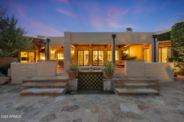 back house at dusk featuring a patio