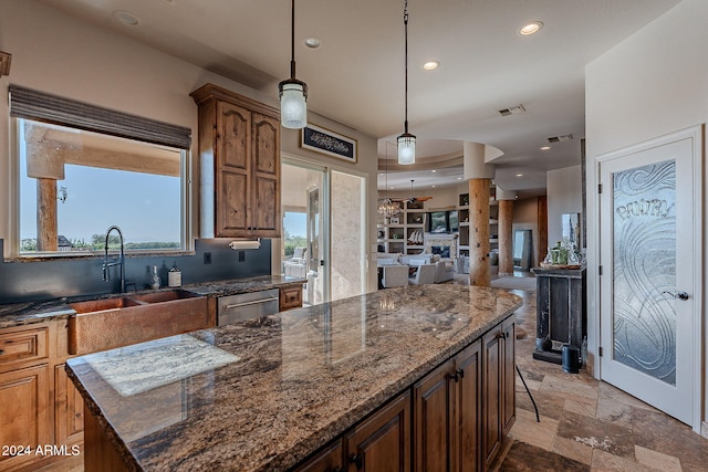 kitchen with dark stone countertops, a center island, stainless steel dishwasher, and a breakfast bar area