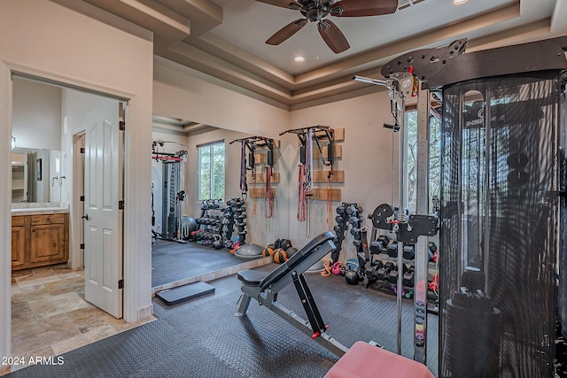 workout room featuring ceiling fan and a raised ceiling