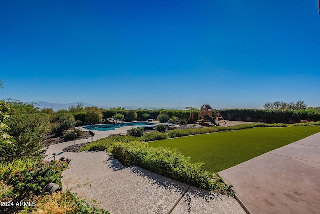 view of home's community featuring a mountain view, a playground, a lawn, and a swimming pool