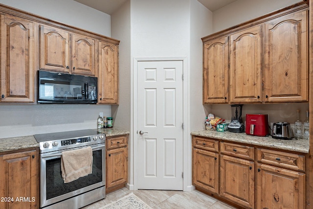 kitchen featuring electric stove, light tile patterned flooring, and light stone counters