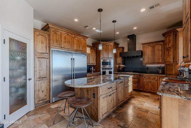 kitchen with sink, a center island, stainless steel appliances, dark stone counters, and premium range hood