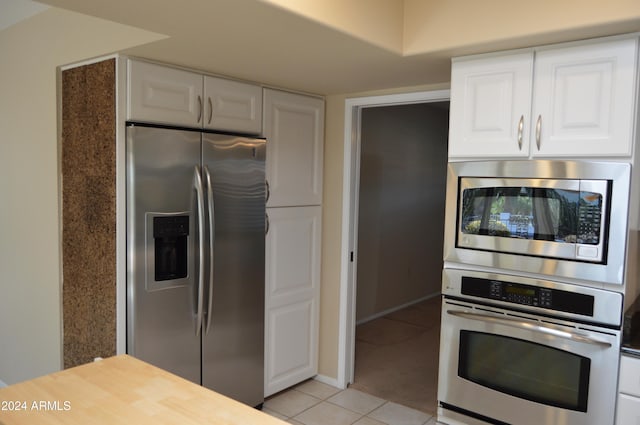 kitchen with white cabinets, light tile patterned floors, and stainless steel appliances