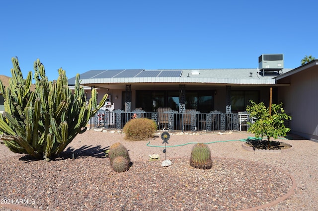 back of property featuring solar panels and central AC unit