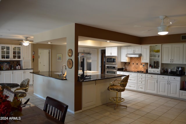 kitchen with white cabinets, stainless steel appliances, tasteful backsplash, and ceiling fan