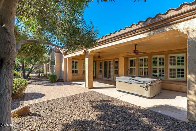 back of property with a hot tub, a patio area, and ceiling fan