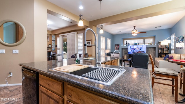 kitchen featuring black dishwasher, sink, ceiling fan, decorative light fixtures, and dark stone countertops