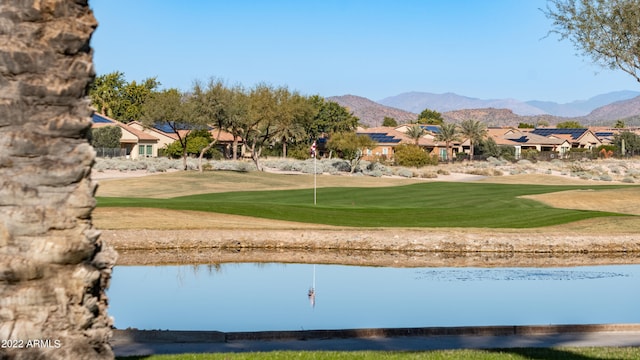 view of home's community with a water and mountain view and a lawn