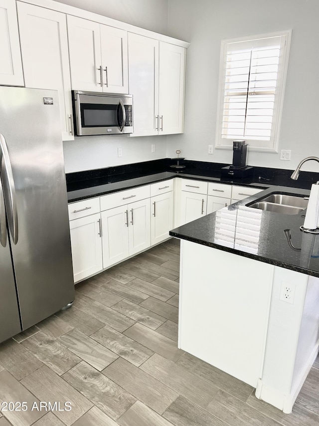 4956 S Leisure Way, Gilbert, AZ 85298 - kitchen with stainless steel appliances, a sink, white cabinets, light wood finished floors, and dark countertops
