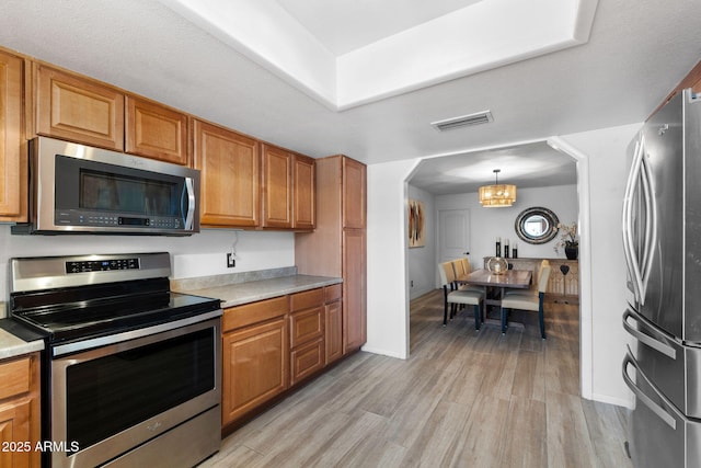 2804 N Nebraska St, Chandler, AZ 85225 - kitchen featuring stainless steel appliances, arched walkways, light wood-type flooring, and brown cabinetry
