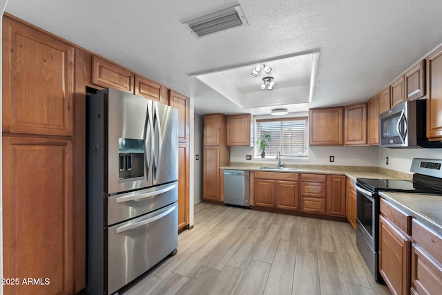 2804 N Nebraska St, Chandler, AZ 85225 - kitchen with appliances with stainless steel finishes, a sink, brown cabinetry, light wood finished floors, and a textured ceiling