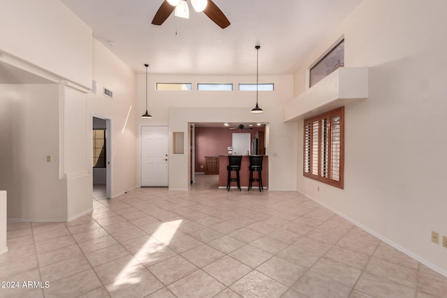 unfurnished living room with ceiling fan, a high ceiling, and light tile patterned floors