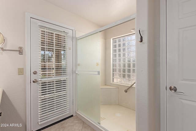 bathroom with tile patterned flooring, a shower with shower door, and a wealth of natural light