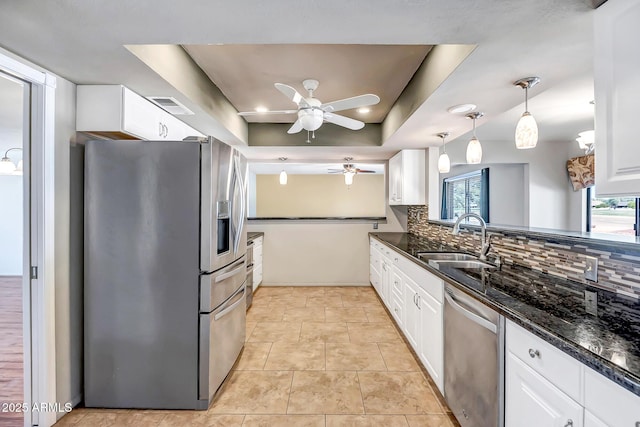 kitchen with backsplash, a tray ceiling, white cabinets, stainless steel appliances, and a sink