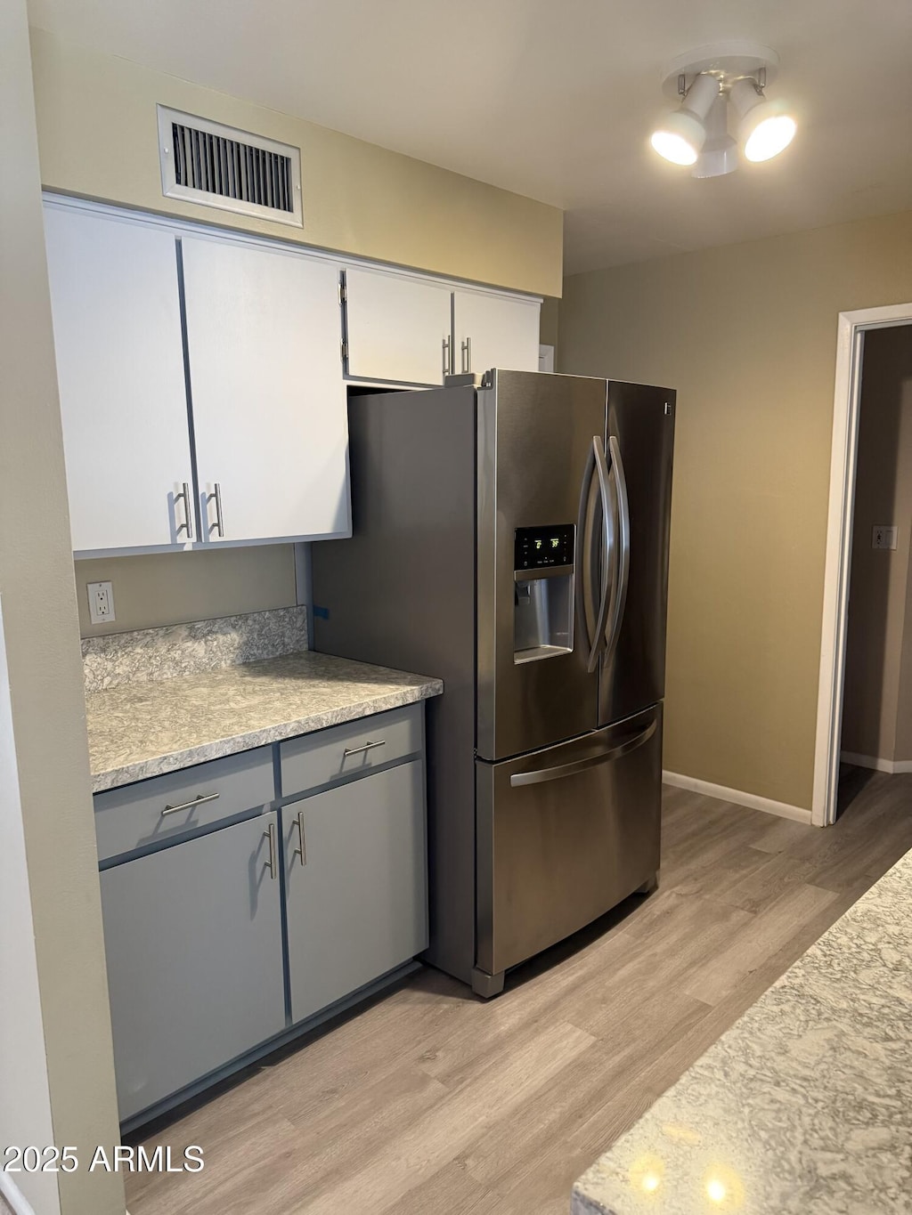 6048 E Des Moines St, Mesa, AZ 85205 - kitchen with stainless steel fridge, light wood-style floors, and white cabinetry