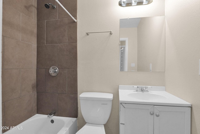 full bathroom featuring tiled shower / bath, vanity, and toilet