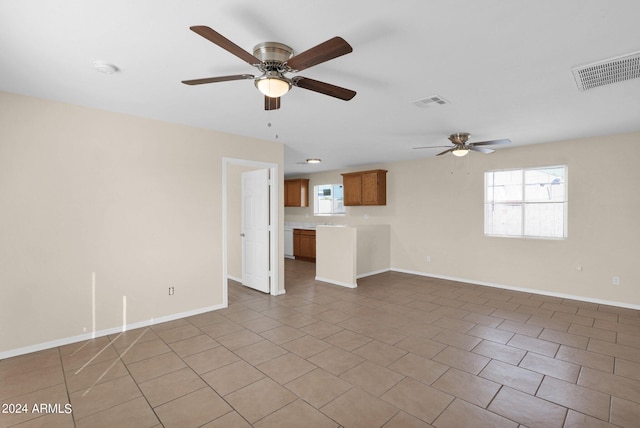 unfurnished living room with ceiling fan, a wealth of natural light, and tile patterned flooring