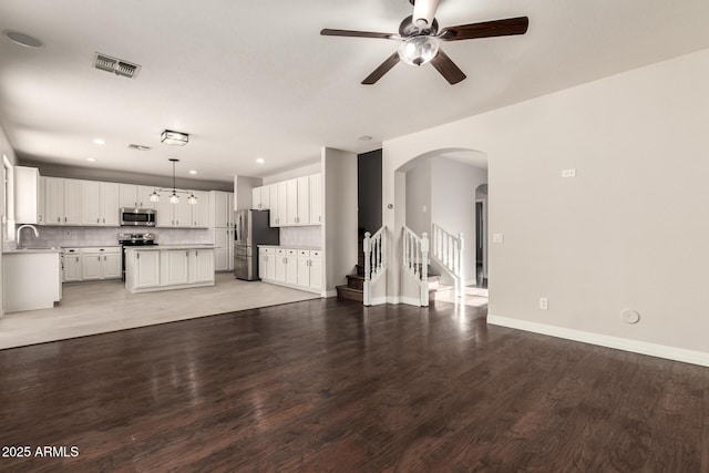 unfurnished living room with wood-type flooring, sink, and ceiling fan