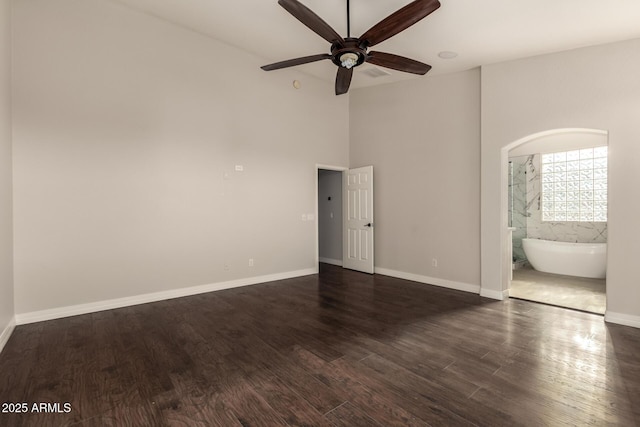 spare room with ceiling fan, a towering ceiling, and dark hardwood / wood-style flooring