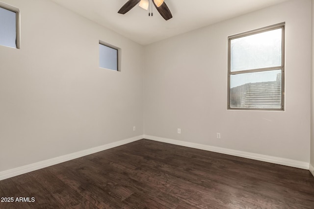 empty room with dark wood finished floors, a ceiling fan, and baseboards