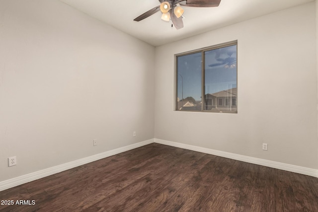 spare room with baseboards, a ceiling fan, and dark wood-style flooring