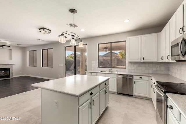 kitchen featuring stainless steel appliances, a center island, sink, and white cabinets