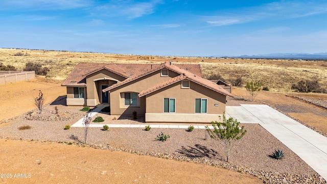 view of front of home featuring fence, stucco siding, concrete driveway, and a tile roof