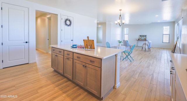 kitchen with hanging light fixtures, an inviting chandelier, light wood-style floors, light countertops, and brown cabinetry