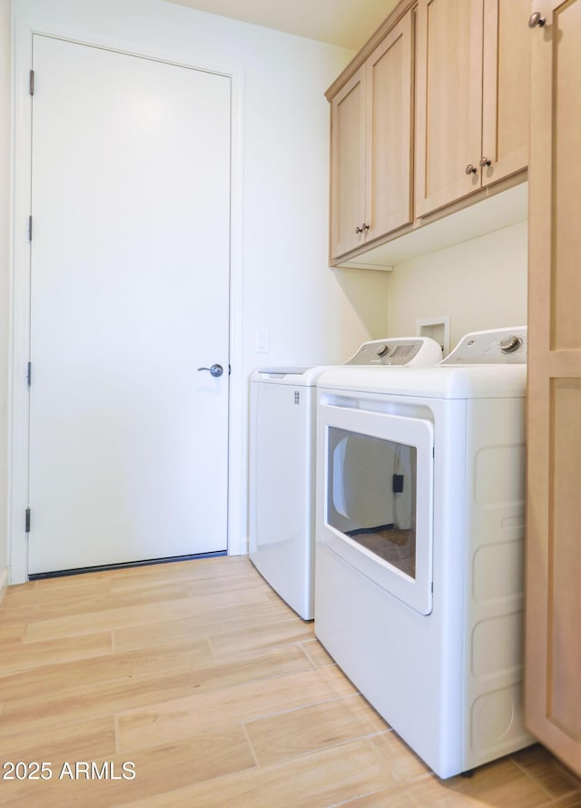 laundry area with light wood-style flooring, cabinet space, and washer and dryer