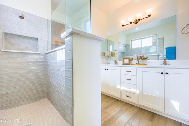 full bathroom featuring double vanity, a sink, walk in shower, and wood finished floors