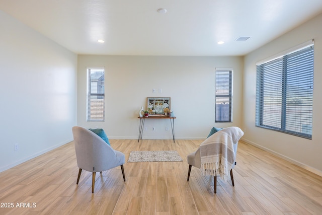 living area featuring baseboards, plenty of natural light, light wood-style flooring, and visible vents