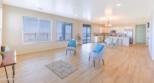 living area with an inviting chandelier, baseboards, light wood-style floors, and recessed lighting